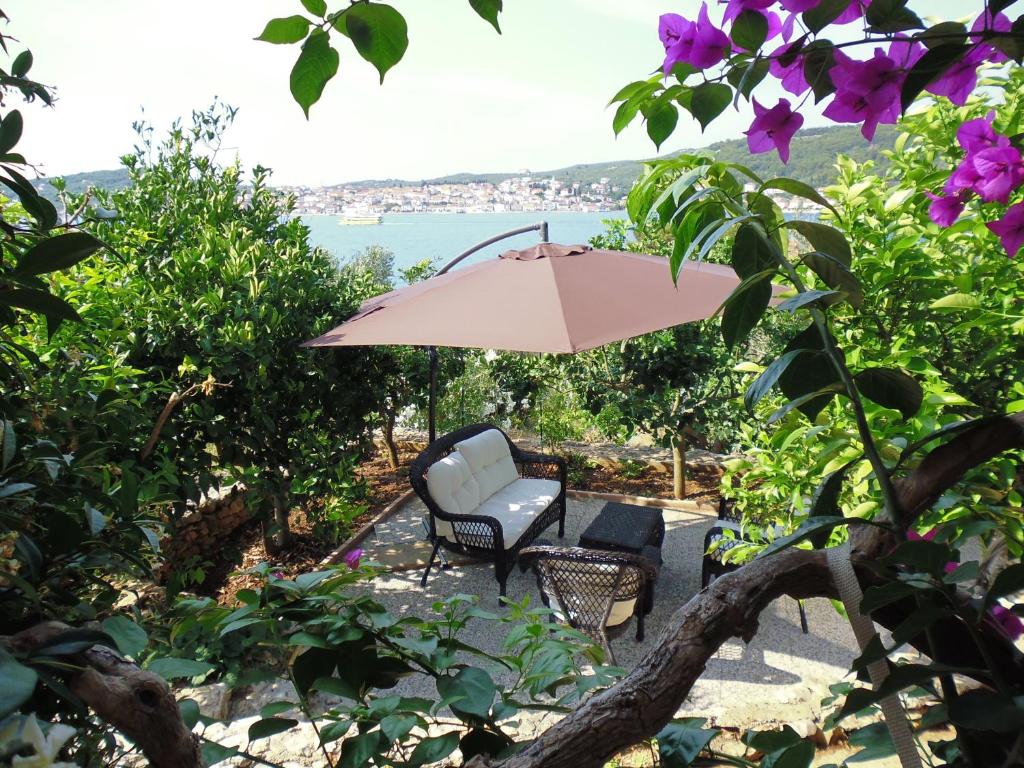 une terrasse avec une chaise et un parasol dans l'établissement Apartment Pilatus Ošljak, à Preko