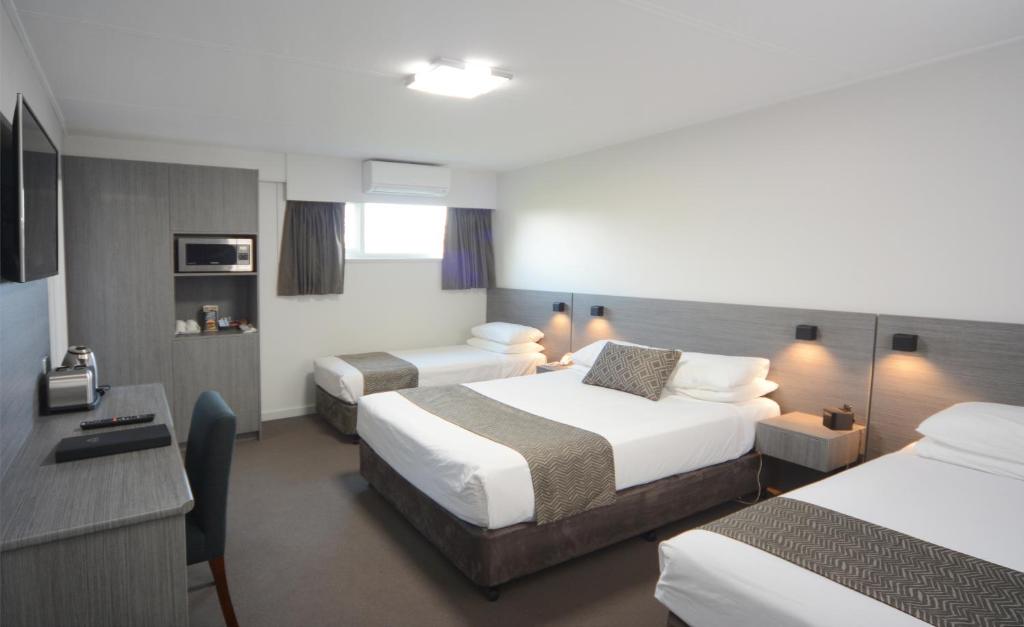 a hotel room with two beds and a desk at Bridge Hotel in Smithton