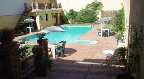 a swimming pool with a table and chairs and an umbrella at Hotel Paris in Lanjarón