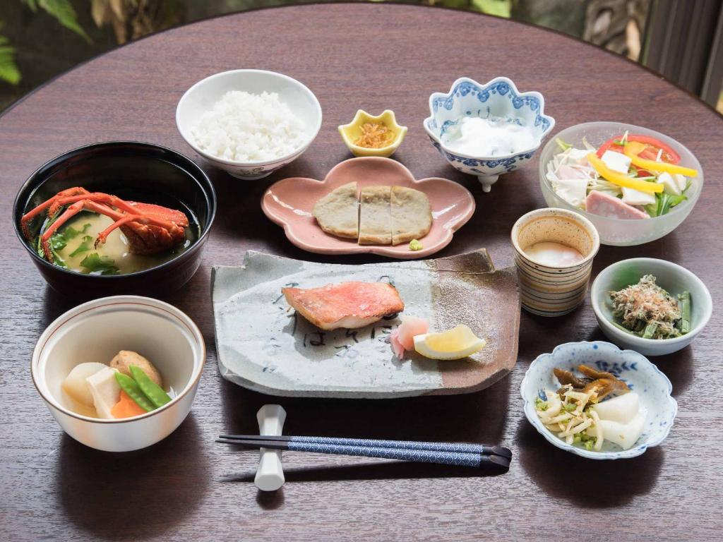 a table with bowls and plates of food on it at Hotel Hagoromo in Shizuoka