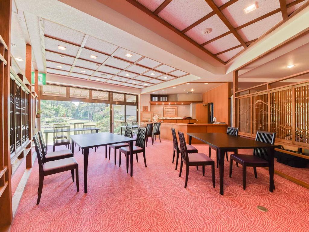 a dining room with tables and chairs and a kitchen at Hotel Hagoromo in Shizuoka