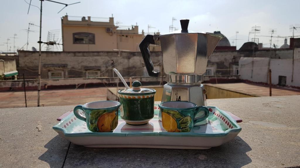 tre tazze di caffè sedute su un vassoio con uno spremiagrumi di Il Miracolo a Napoli