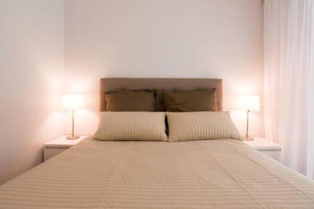 マンドリュー・ラ・ナプールにあるRiviera Homeのベッドルーム1室(大型ベッド1台、ランプ2つ付)