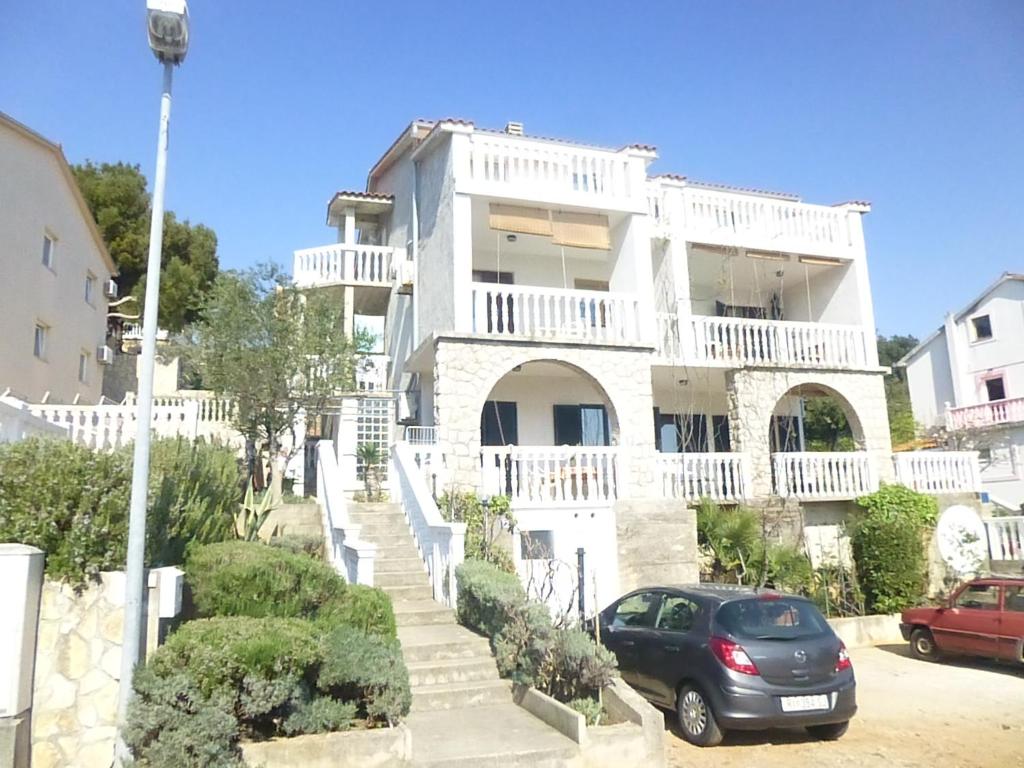 a white house with a car parked in front of it at Apartments Vila Lavanda in Omišalj