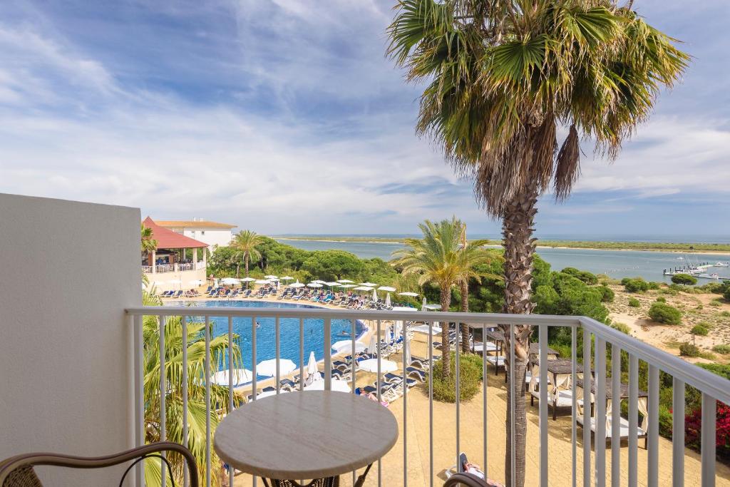 a balcony with a table and chairs and a pool at Garden Playanatural - Adults Only in El Rompido