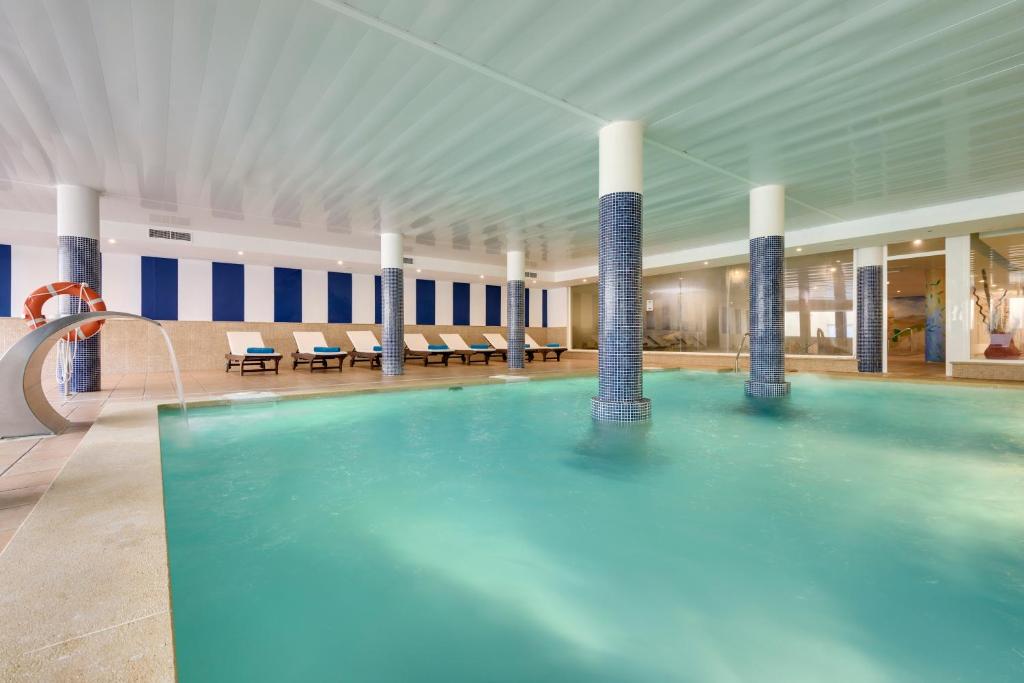 a large pool in a hotel with chairs and tables at Garden Playanatural - Adults Only in El Rompido
