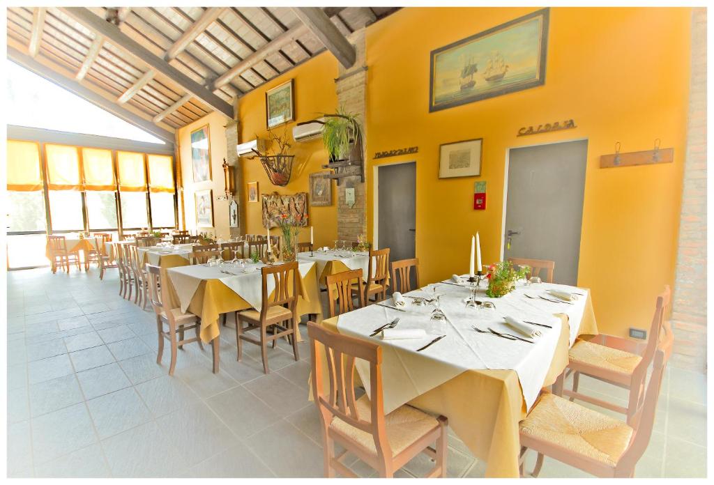 a dining room with tables and chairs and yellow walls at Corte Dossello in Migliaro
