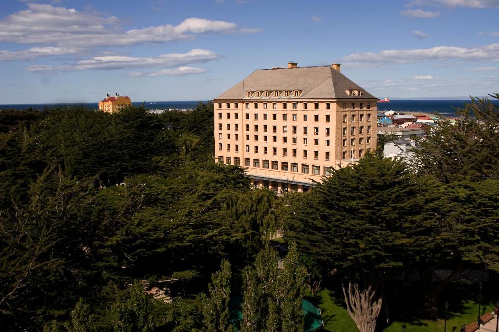 un edificio alto con techo sobre árboles en Hotel Cabo De Hornos, en Punta Arenas