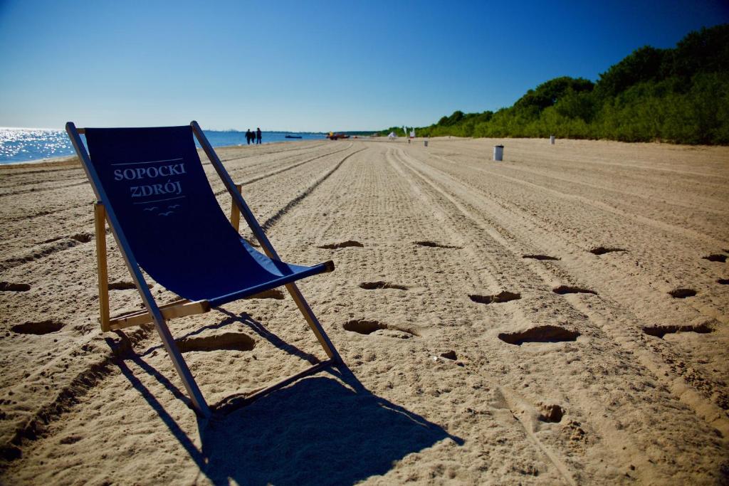 uma cadeira de praia azul sentada numa praia arenosa em Sopocki Zdrój Apartments em Sopot