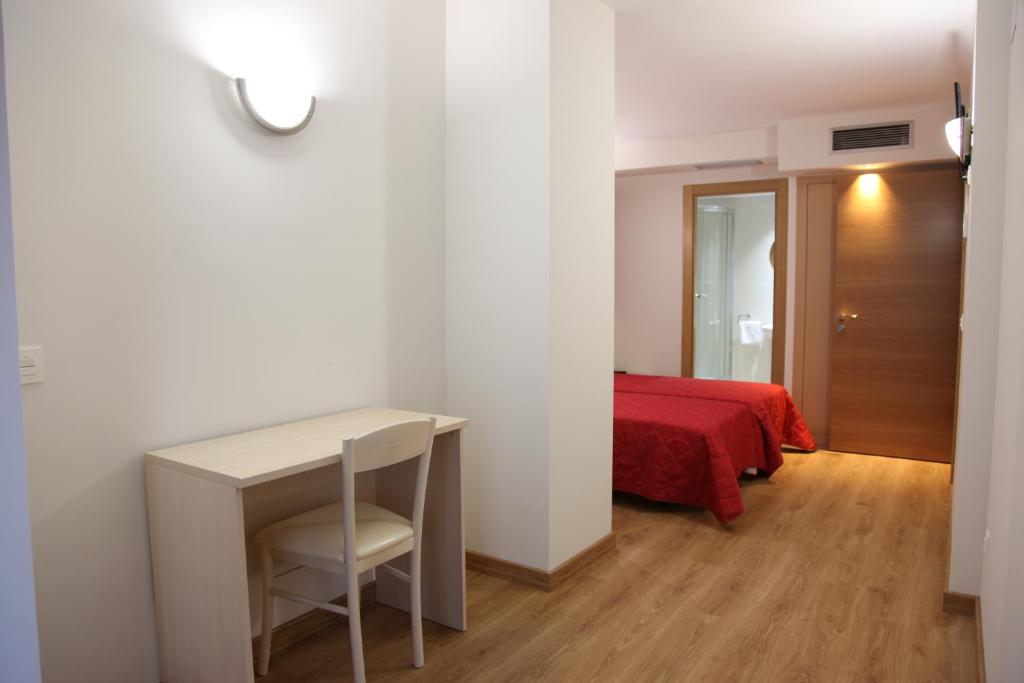 1 dormitorio con escritorio y cama roja en Hostal Santel San Marcos en Salamanca