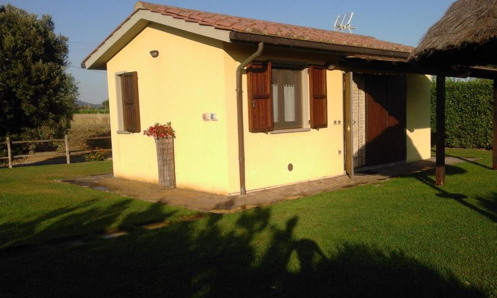 una piccola casa gialla con finestra in un cortile di Monolocale con giardino a Castiglione della Pescaia