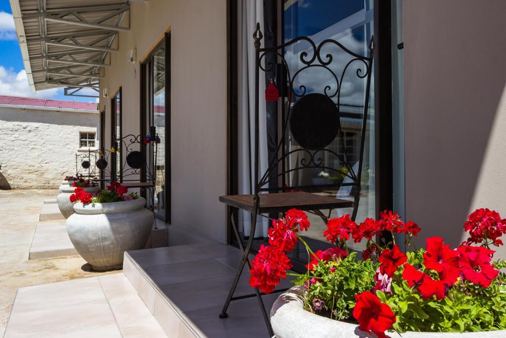 a patio with red flowers in vases next to a building at Hazeldene Accommodation in Colesberg