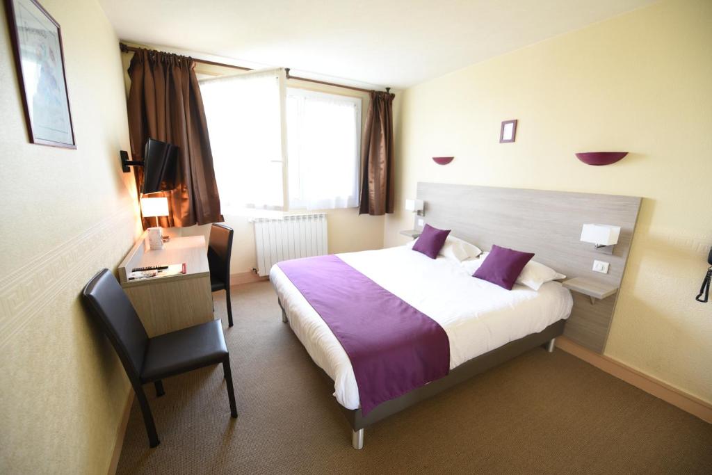 een hotelkamer met een groot bed en een bureau bij Hôtel Continental in Vierzon