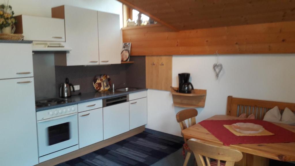 een keuken met witte kasten en een tafel en een eetkamer bij Apart Martina in Ried im Oberinntal