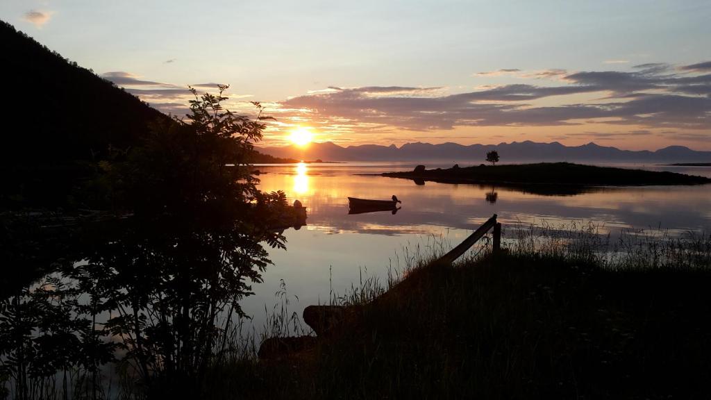 zachód słońca nad jeziorem z łodzią w wodzie w obiekcie Prima Lofoten w mieście Myrland