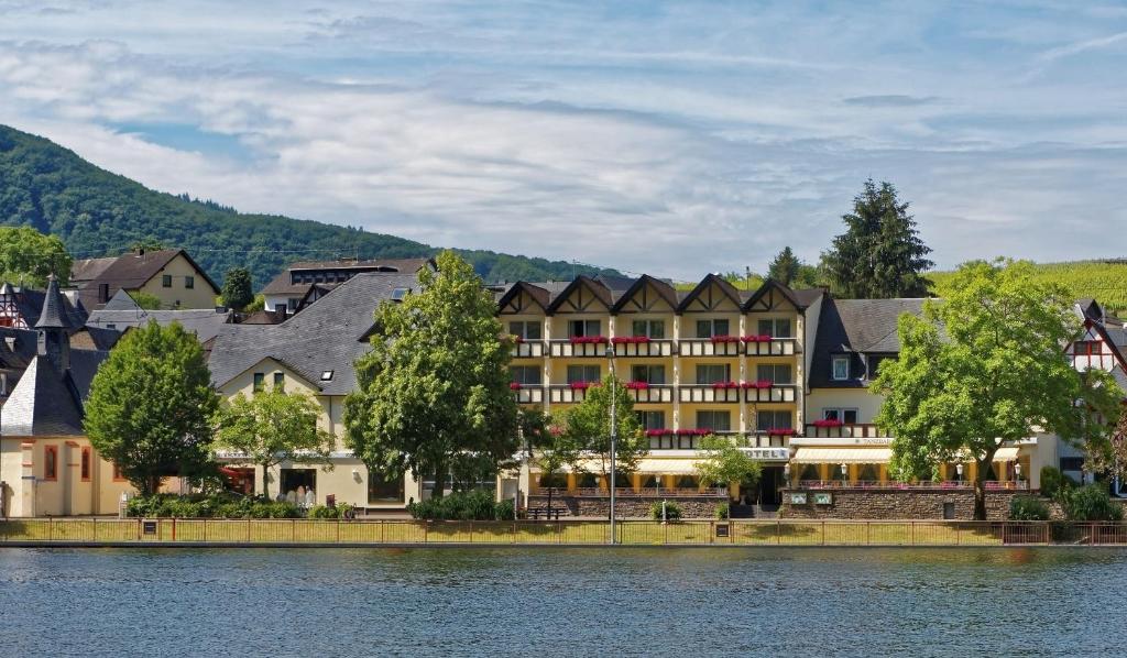 un groupe de bâtiments à côté d'une masse d'eau dans l'établissement Moselstern Hotel Fuhrmann, à Ellenz-Poltersdorf