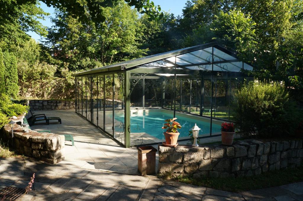 a glass greenhouse with a swimming pool in it at la maison des chartreux in Brives-Charensac