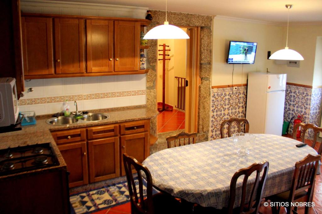 a kitchen with a table and a sink and a refrigerator at Casa do Outeirinho in Sabugueiro