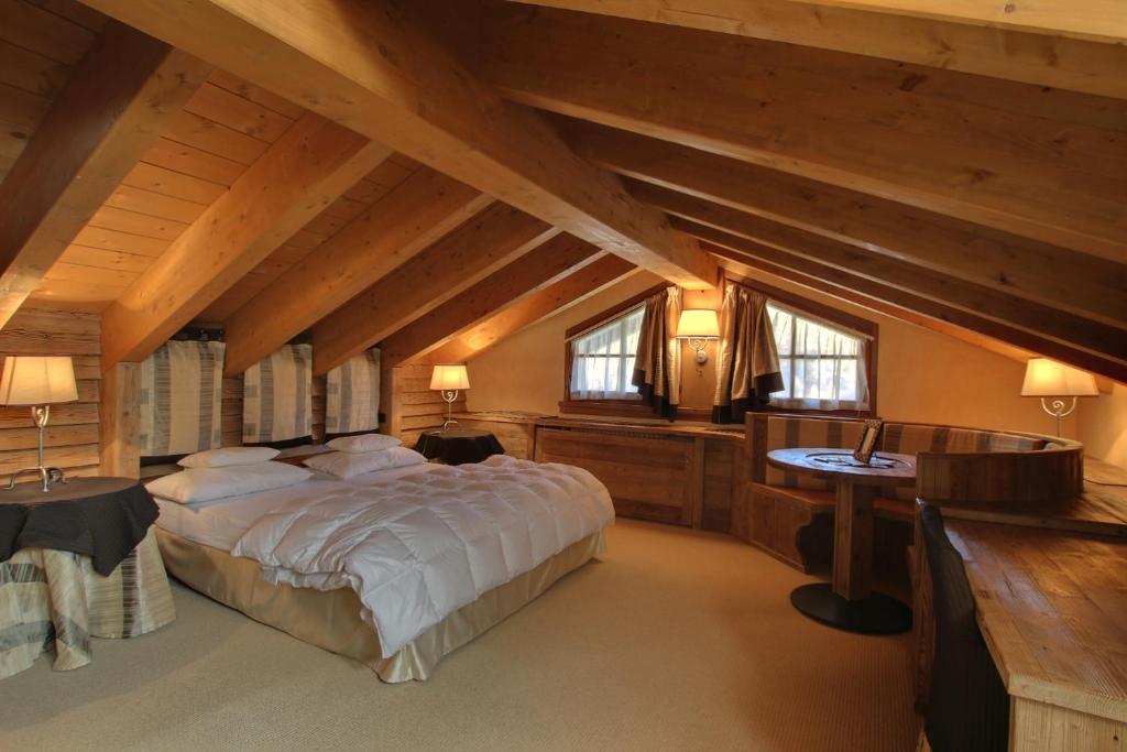 a bedroom with a large bed and a desk and windows at Hotel Bait de Angial in Livigno