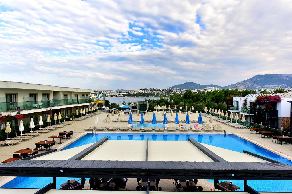 een uitzicht op een zwembad in een resort met stoelen en parasols bij Jasmin Beach Hotel in Gümbet
