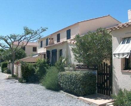 ein Haus mit einem Zaun und Büschen davor in der Unterkunft maison de la plage in Le Grau-du-Roi