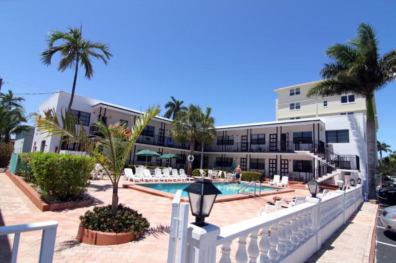 een resort met een zwembad en palmbomen en een gebouw bij Napoli Belmar Resort in Fort Lauderdale
