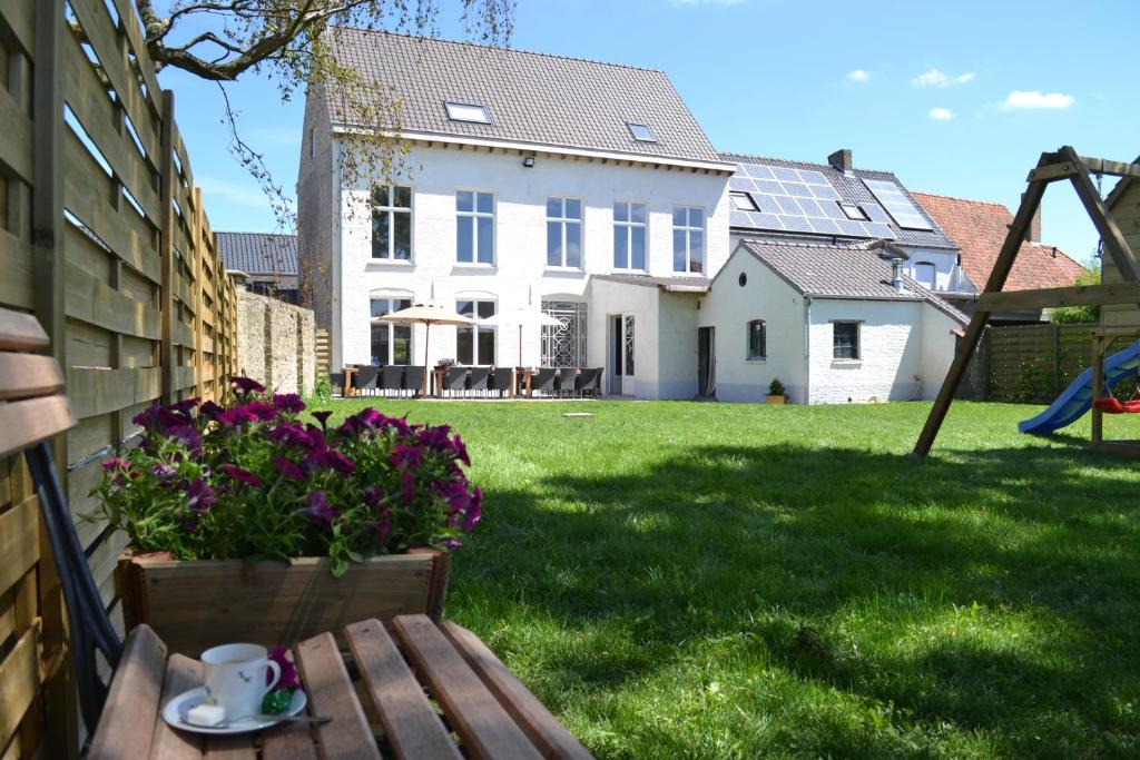 a white house with a table and flowers in the yard at Het Oud Brouwershof in Alveringem