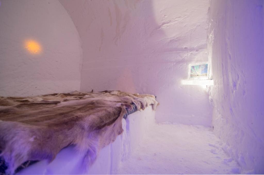 a bed in a room with snow on the walls at Sorrisniva Igloo Hotel in Alta