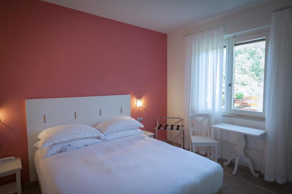 a bedroom with a white bed and a window at Arli Hotel Hideaway Punta Ala - Adults Only in Punta Ala