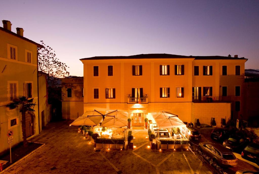 a building with tables and umbrellas in a courtyard at Hotel Clitunno in Spoleto