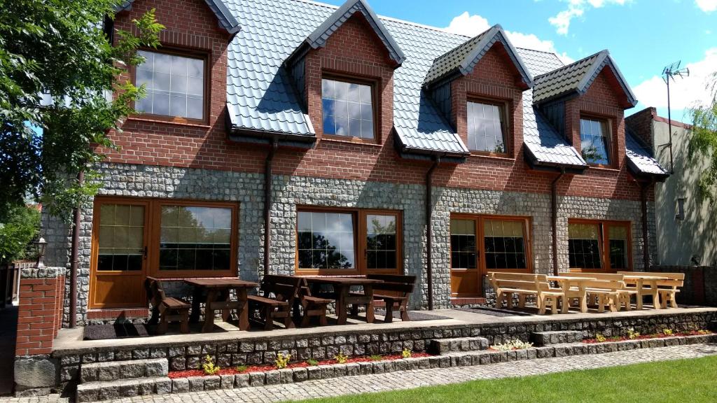 a house with tables and chairs in front of it at Dom Wczasowy Mariza DOMKI LETNISKOWE in Czaplinek