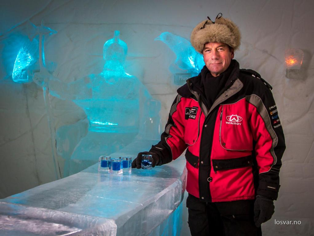 a man standing in front of a table with glasses at Sorrisniva Igloo Hotel in Alta