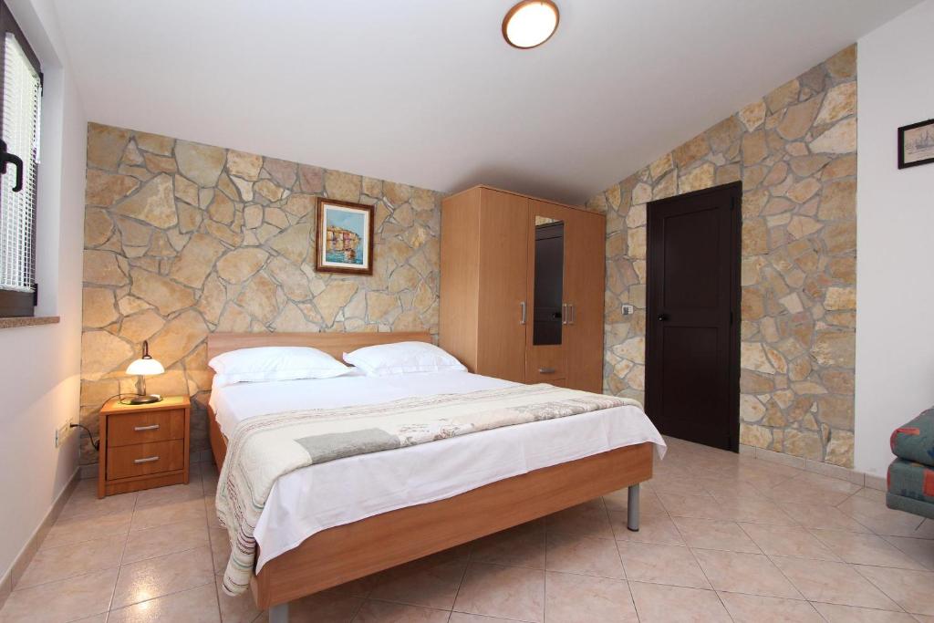 sypialnia z dużym łóżkiem i kamienną ścianą w obiekcie Apartments Marlina w Rovinj
