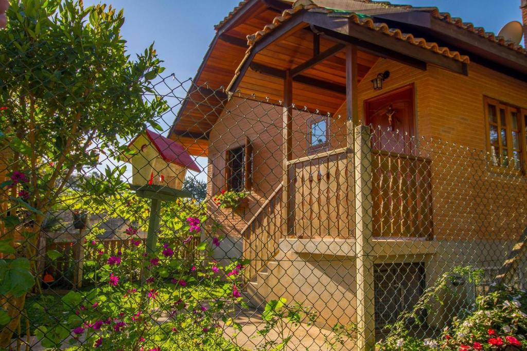 a fence in front of a house with flowers at Casa Pau Brasil in Monte Verde