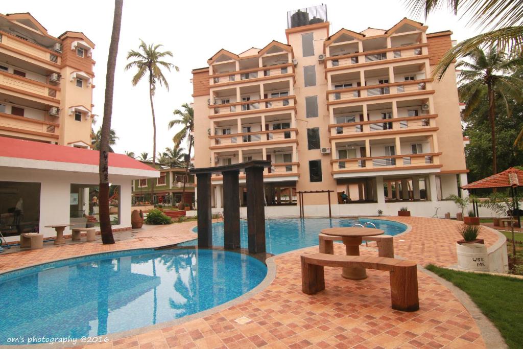 a swimming pool in front of a building at Goa Fiesta in Arpora