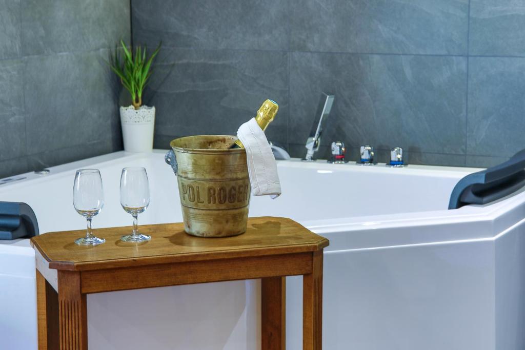 ein Badezimmer mit einer Badewanne und zwei Weingläsern auf dem Tisch in der Unterkunft Suites Residences Spa in Colmar