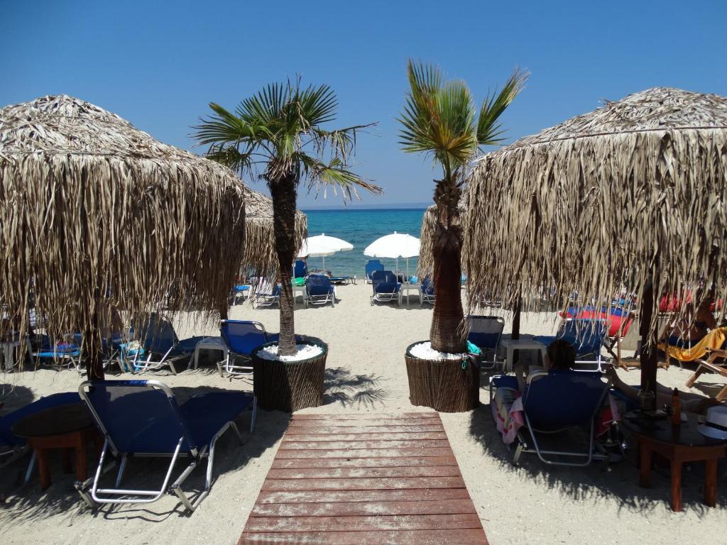 una playa de arena con sillas y sombrillas y el océano en Hotel Rigakis, en Pefkohori