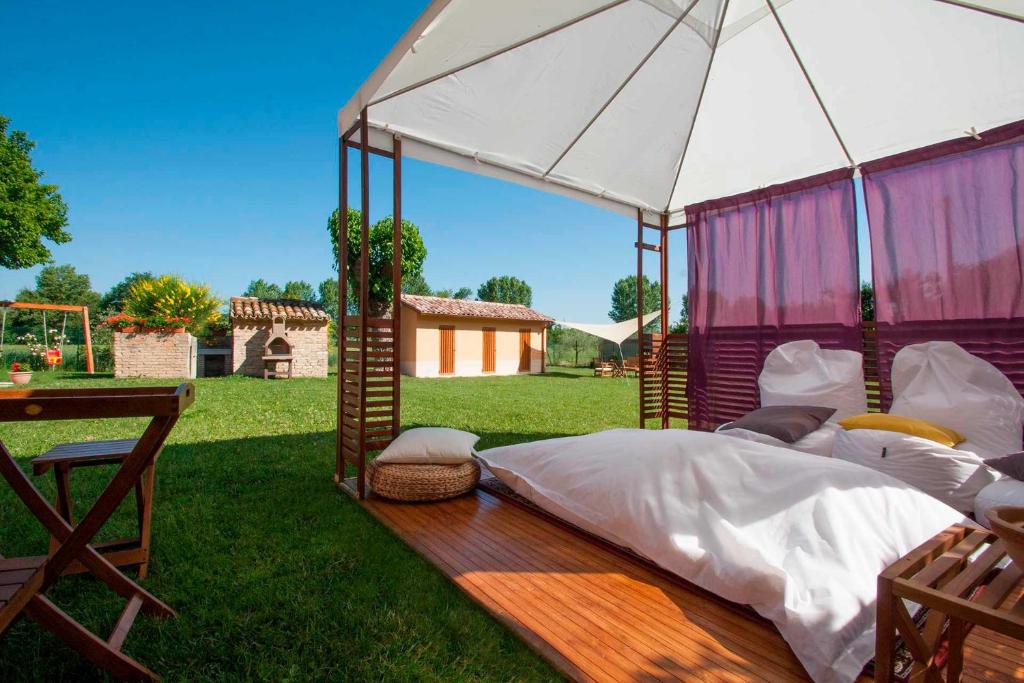 un letto a baldacchino in un campo con un tavolo di Il Poggetto a Corinaldo