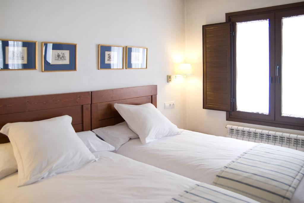 a bedroom with two beds with white sheets and a window at Refugio del Segura in Pontones