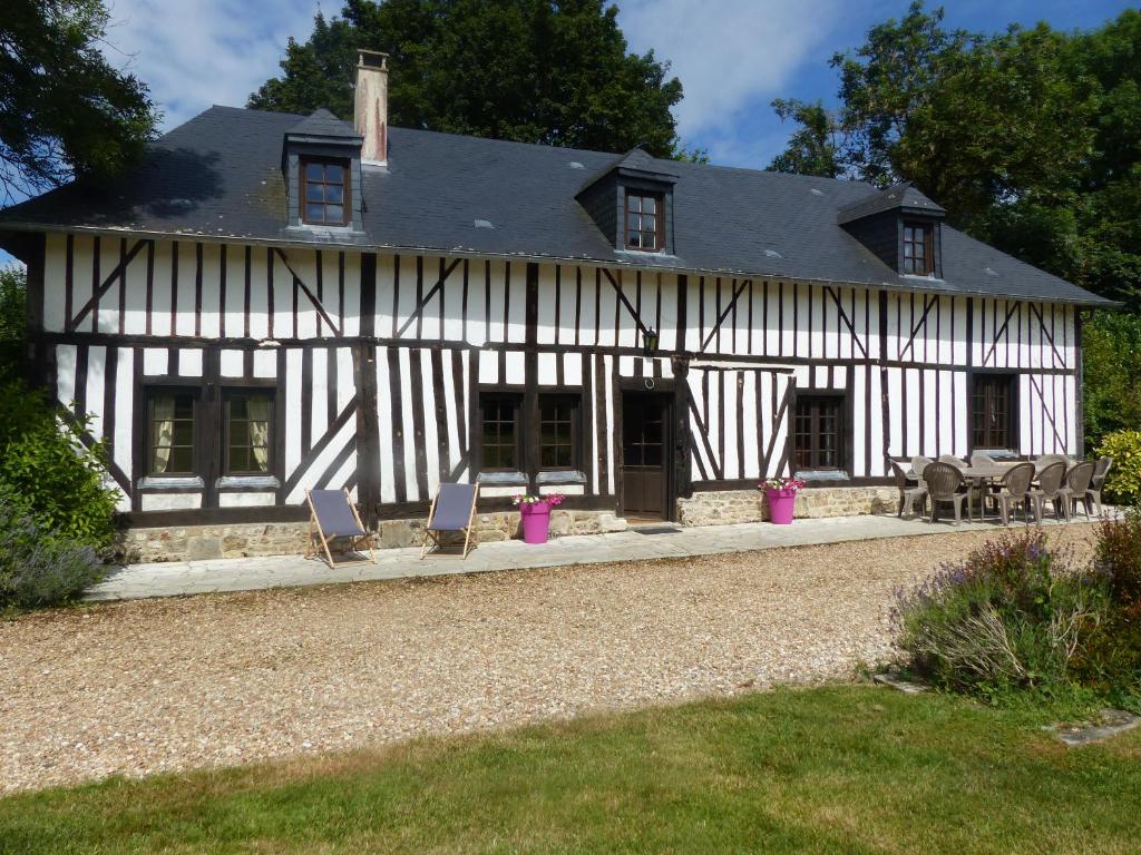 une maison blanche et noire avec des chaises et des tables dans l'établissement Le Domaine des Tostes, à Bonneville-la-Louvet