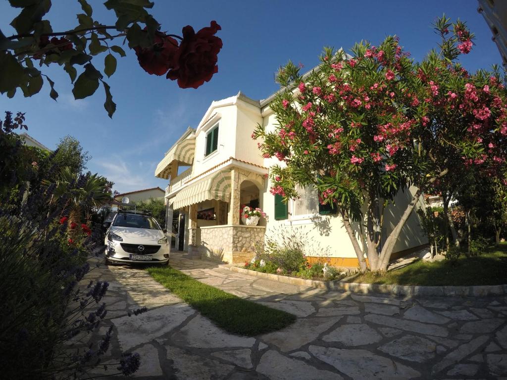 a white car parked in front of a house with flowers at Apartman Veronika in Vrsi
