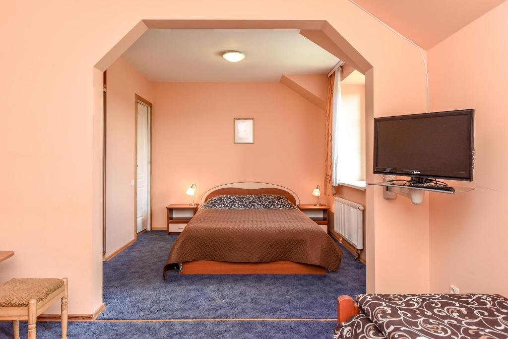 a hotel room with a bed and a flat screen tv at Karklės Kopos in Karklė