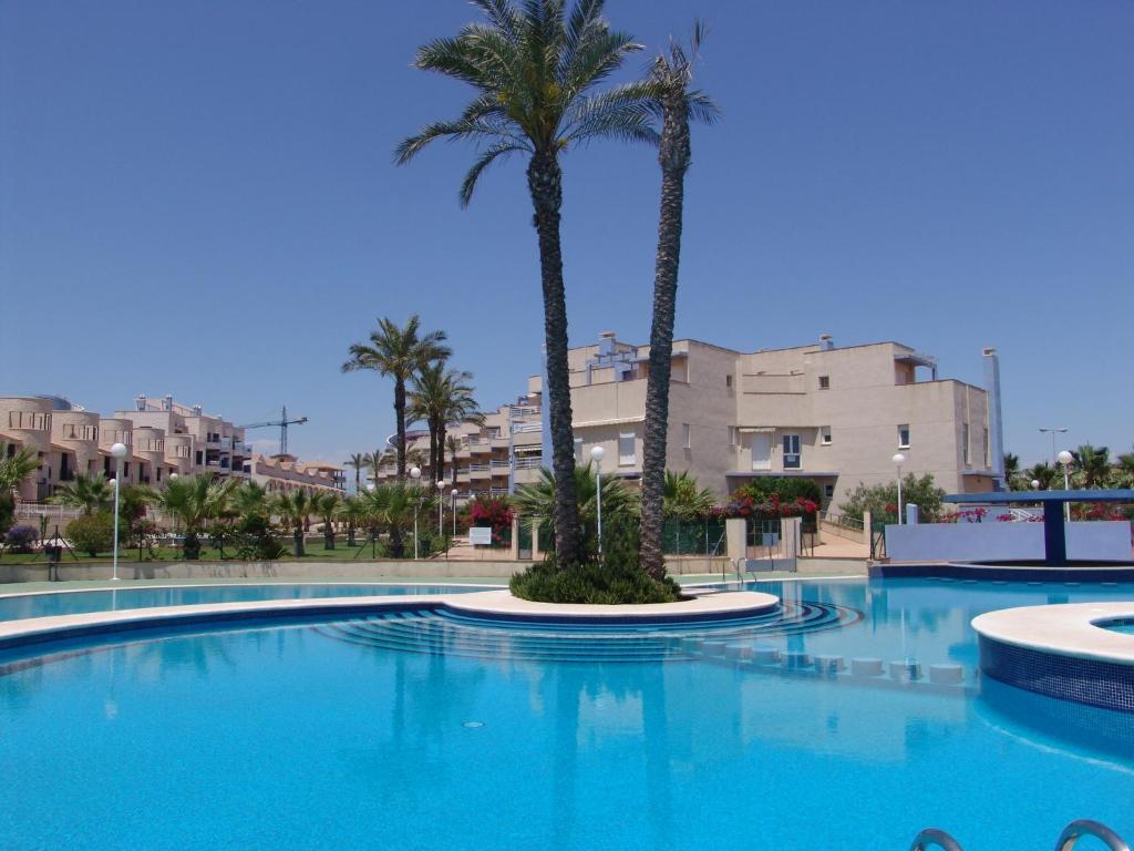 una gran piscina con palmeras y edificios en Calas de Campoamor en Cabo Roig, en Playas de Orihuela