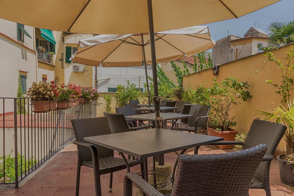 un patio al aire libre con mesas, sillas y sombrillas en Hotel Monica, en Florencia