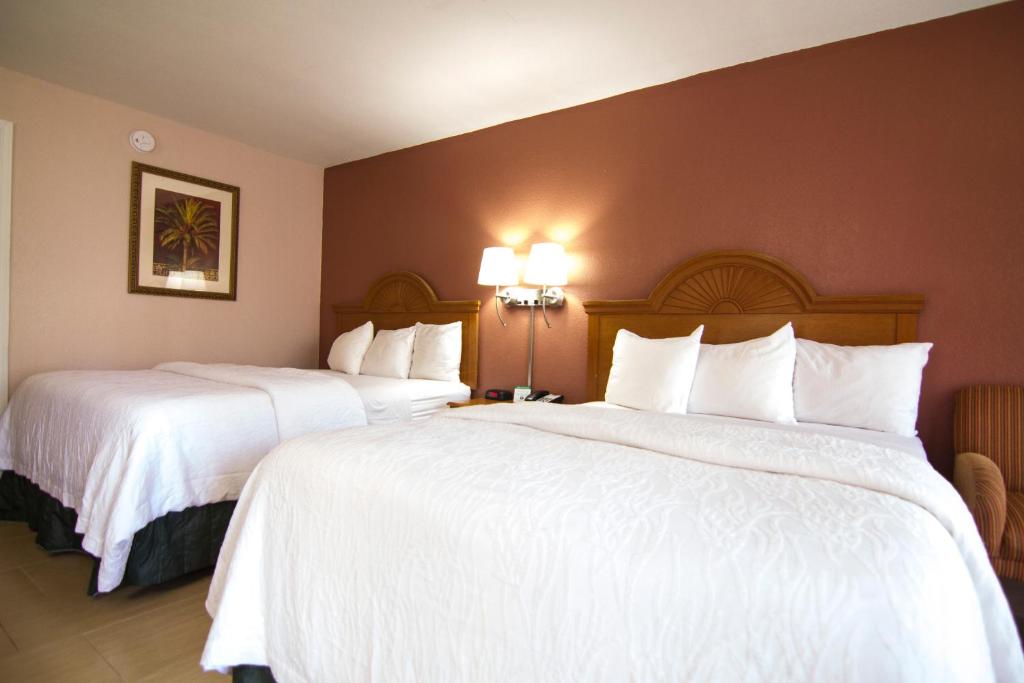 two beds in a hotel room with white sheets at La Copa Hotel in McAllen