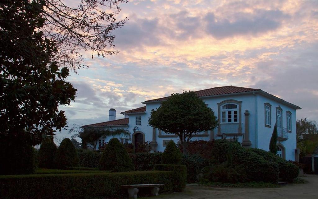 Una casa blanca con un árbol delante. en Quinta da Fata, en Nelas