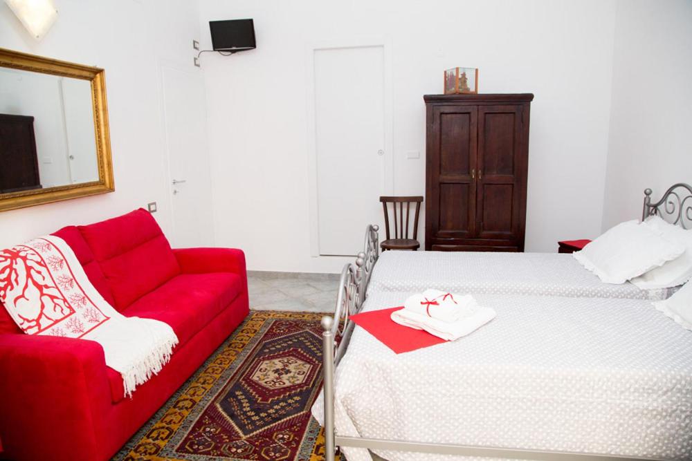 アルゲーロにあるLa Posentoのベッド2台と赤いソファが備わる客室です。