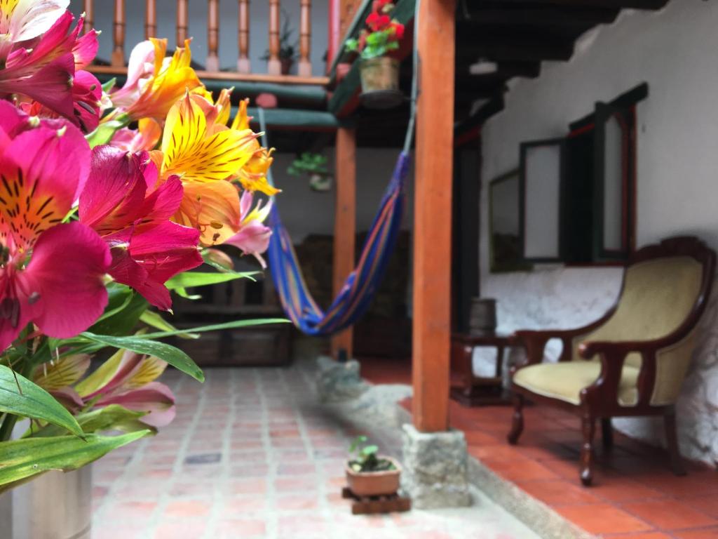 a vase filled with colorful flowers next to a chair at Hotel Otti Colonial in Monguí