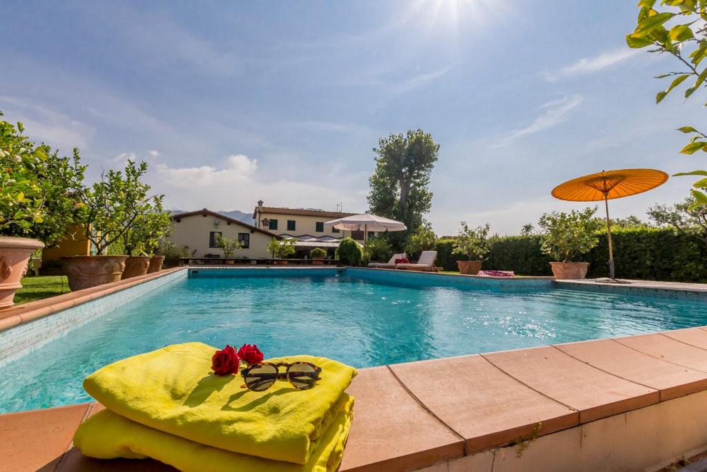 a swimming pool with a towel and sunglasses and an umbrella at Villa Pallina with Pool - Happy Rentals in Massarosa