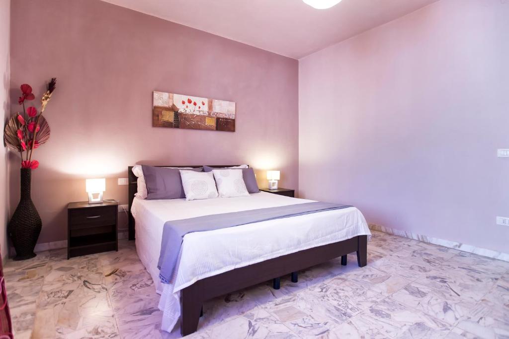 アルゲーロにあるSeaside Holidaysのベッドルーム1室(大型ベッド1台、テーブル2台、ランプ2つ付)